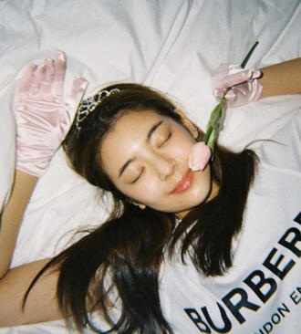 lia (jisoo) from itzy with pink gloves and a pink flower laying in bed